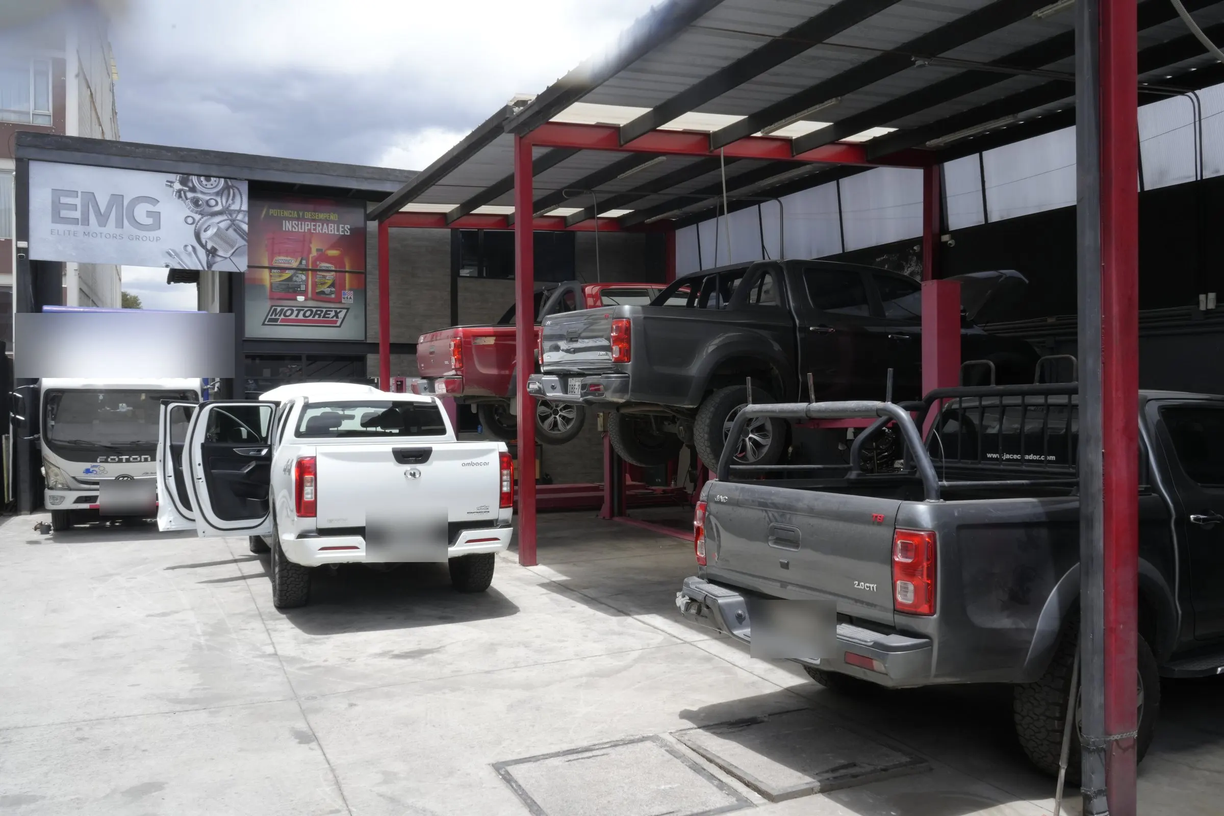 Patio del taller EMG con camionetas y un camión Foton