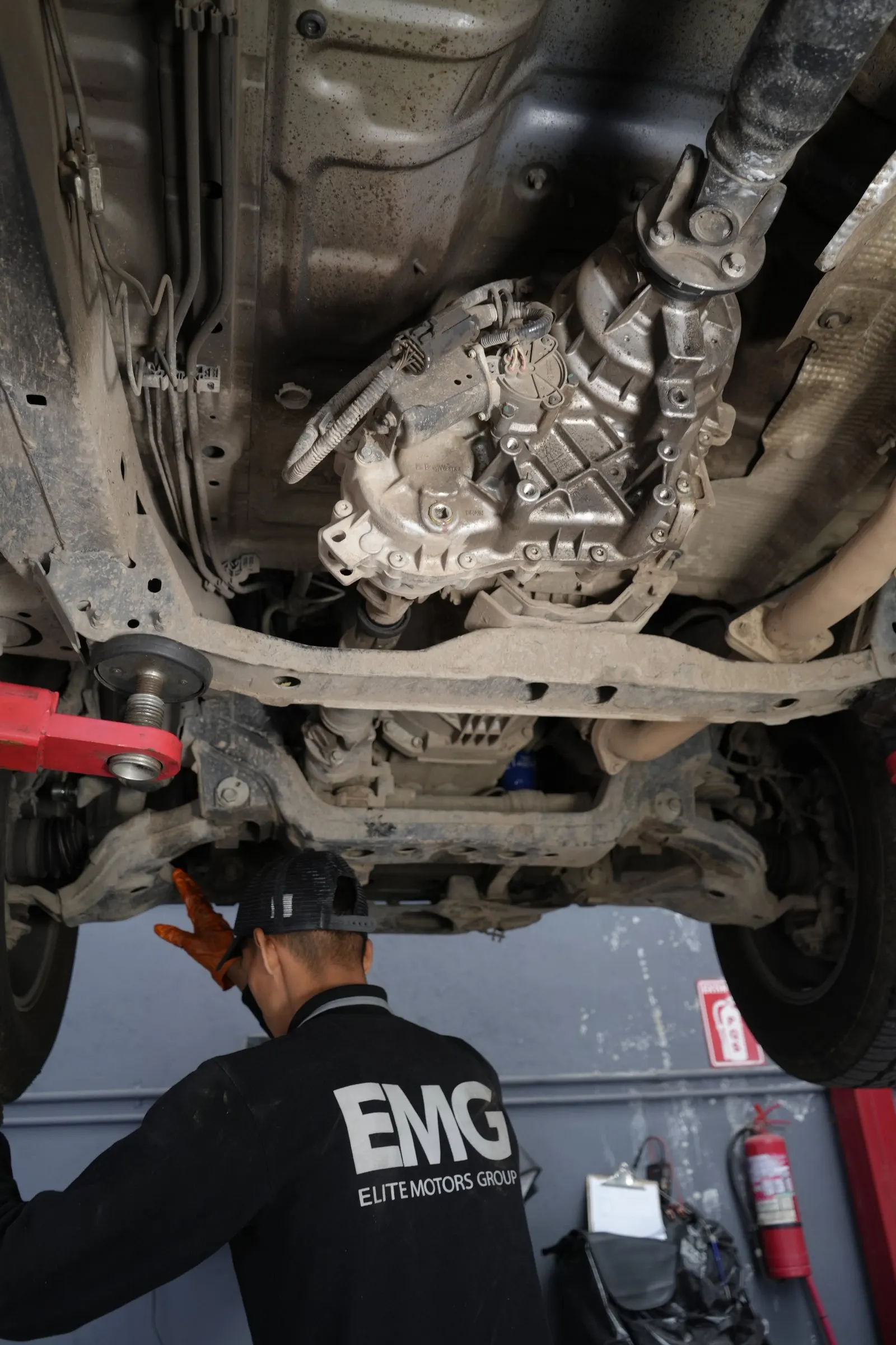 Técnico de EMG revisando la transmisión 4x4 bajo la camioneta
